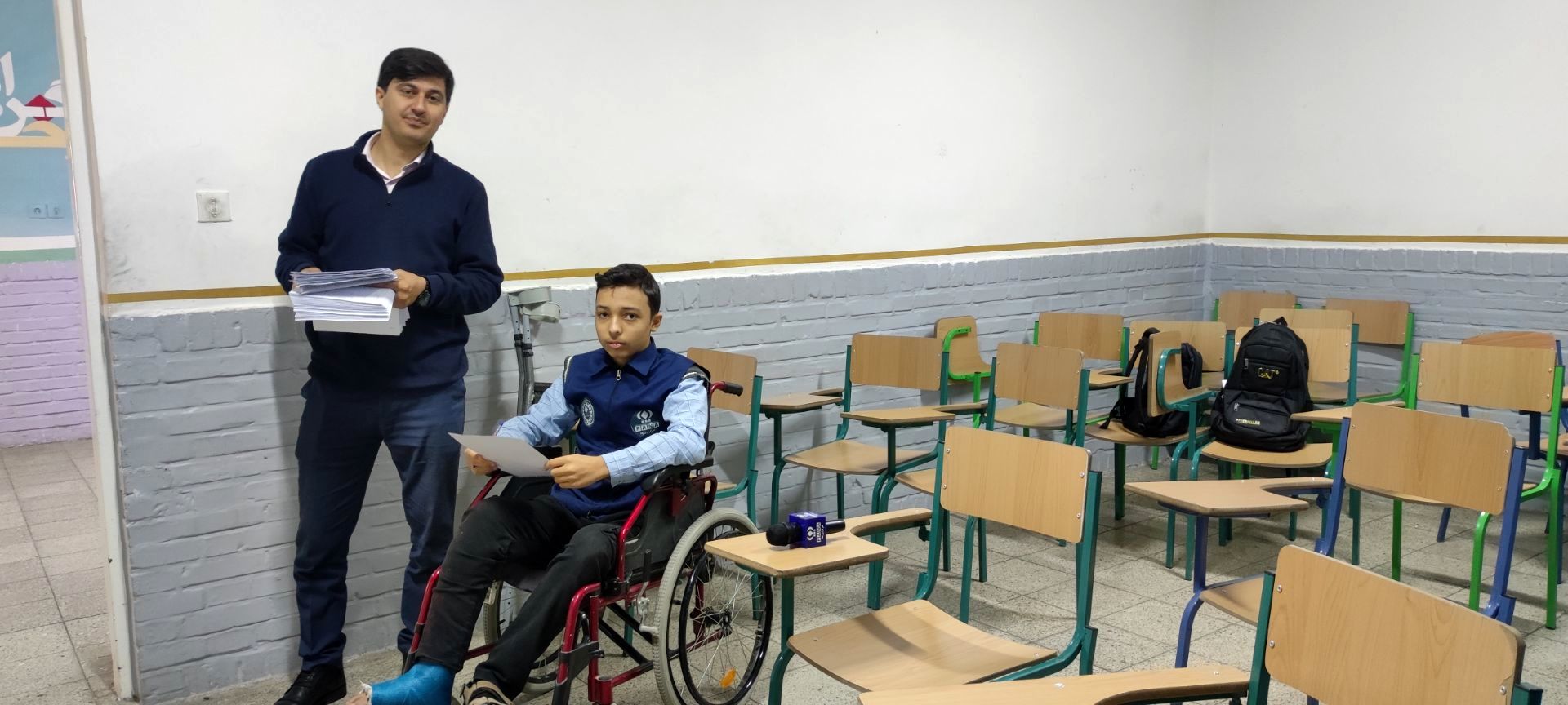 دانش آموز خبرنگار خبرگزاری پانا نشسته بر صندلی چرخدار در پای آزمون نوبت اول